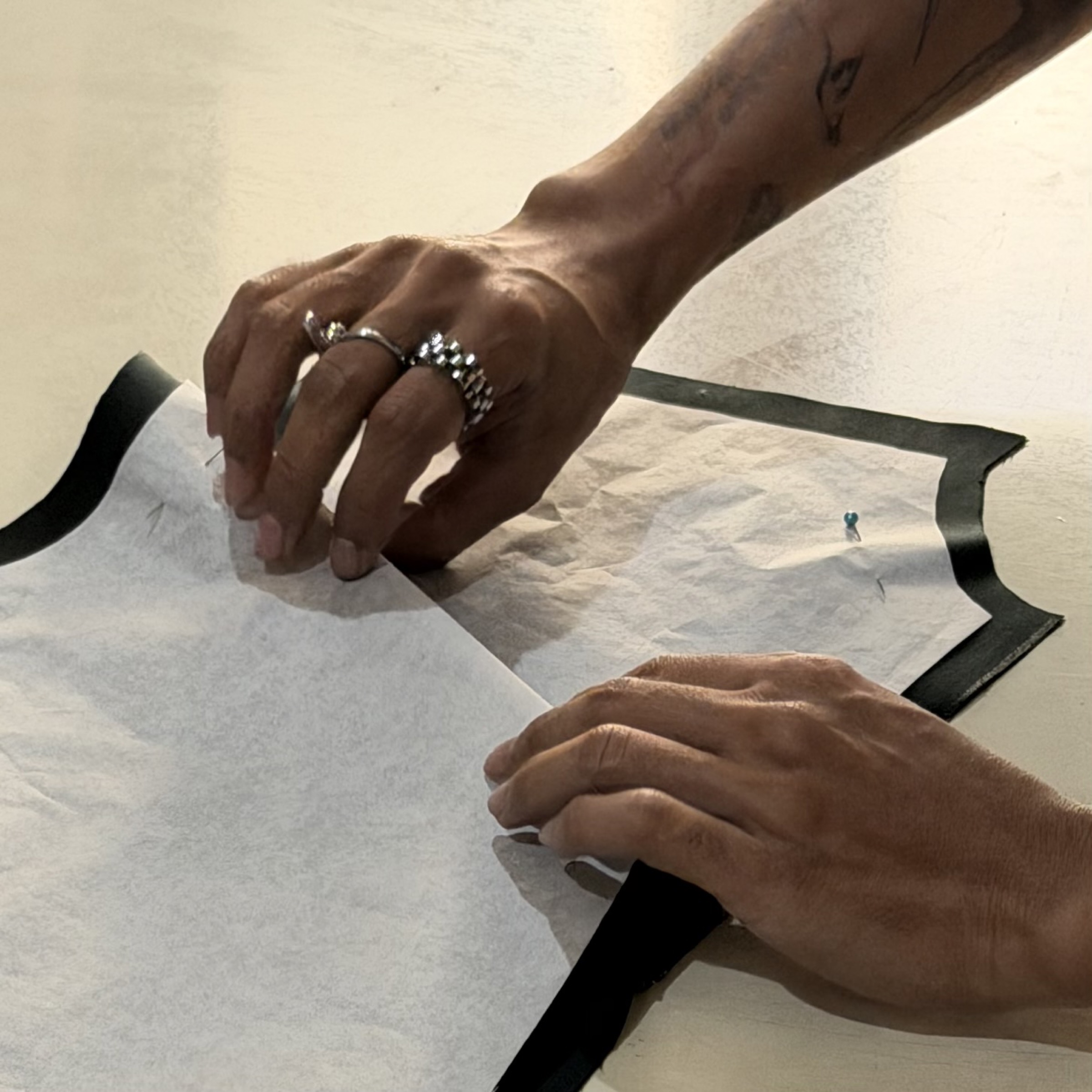 Hands pinning a tissue pattern onto fabric, HITJA workshop